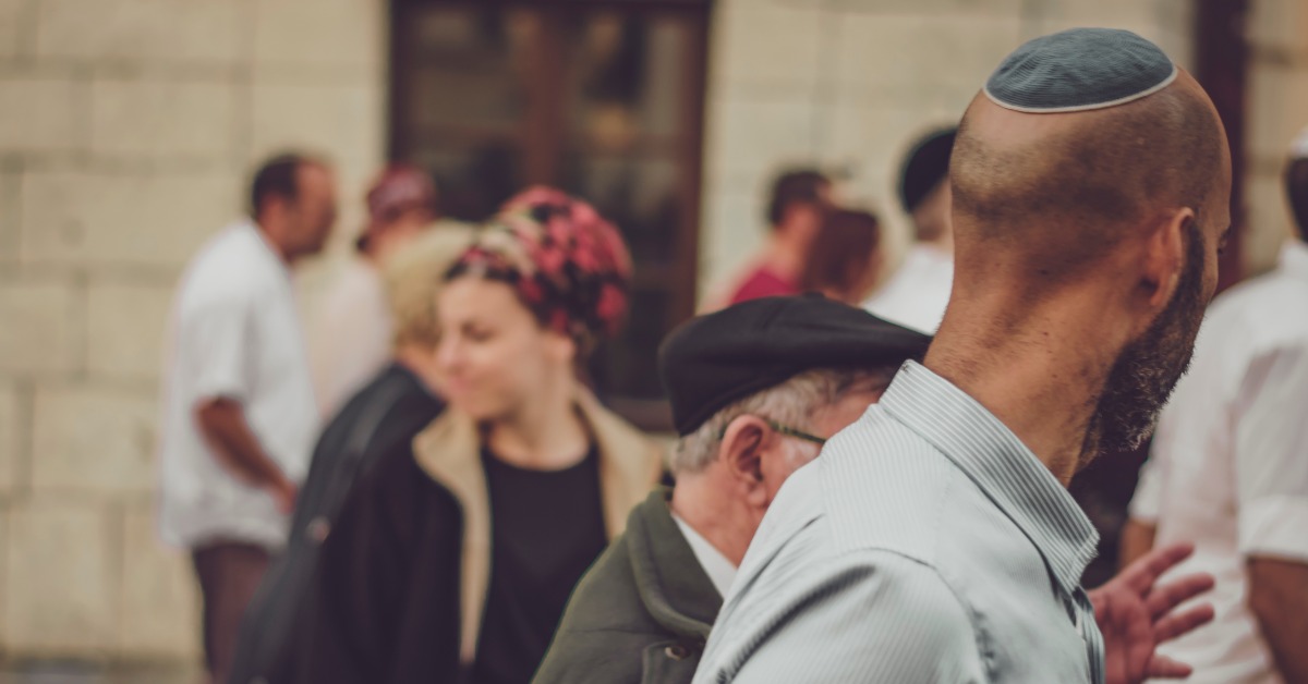 A group of people walking around Israel on a custom tour. One individual is wearing a yamaka on the back of their head.